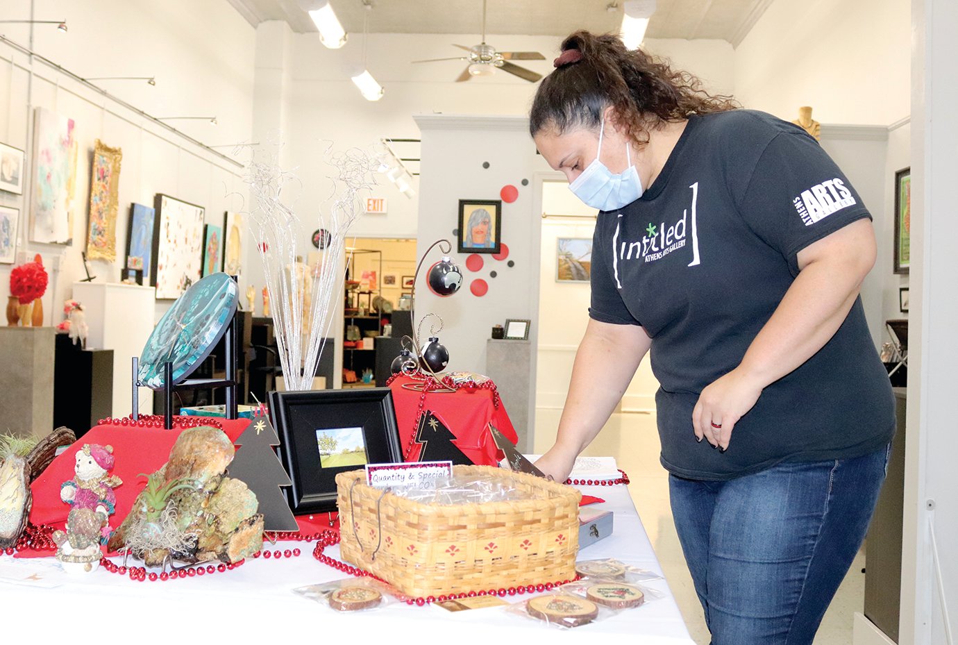 Local artist Kenya Ott arranges holiday displays and sale items Friday at Athens Arts Gallery downtown.